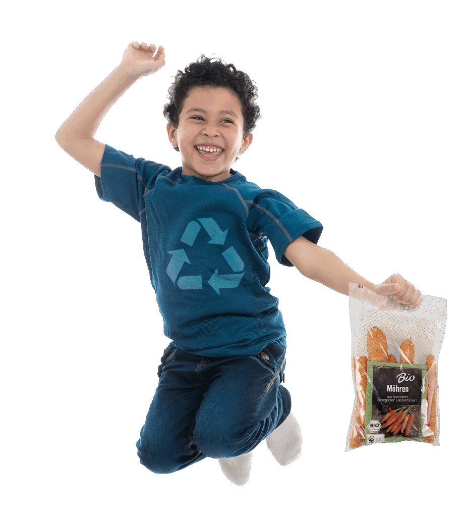 Junge springt in die Höhe, trägt ein Shirt mit Recyclingsymbol und hält einen Möhrenbeutel in der Hand.